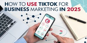 Hand holding smartphone displaying TikTok app interface with text "How to Use TikTok for Business Marketing in 2025," alongside a laptop and notebook, illustrating social media marketing strategies.